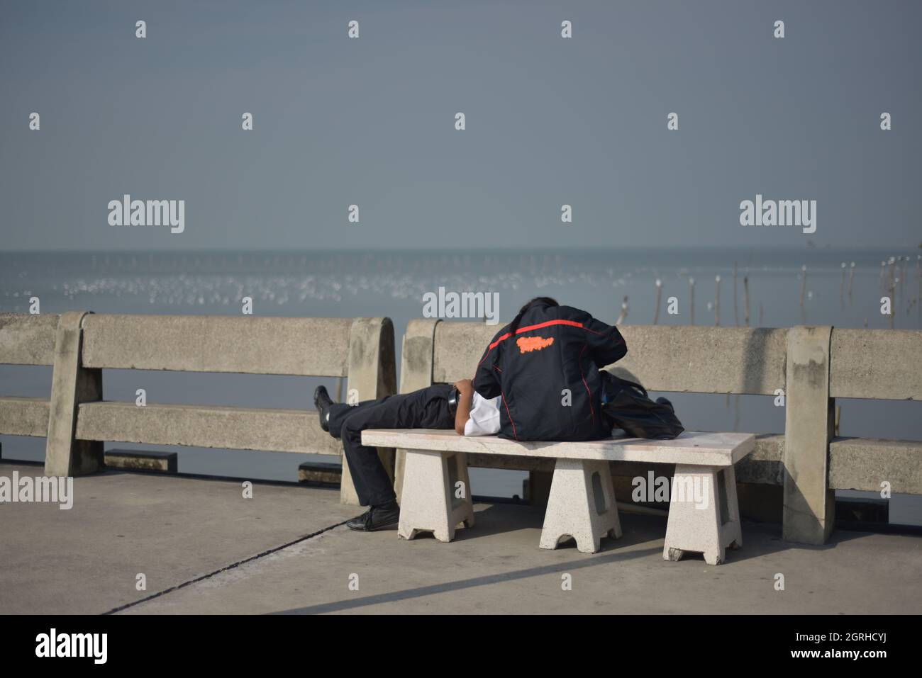 Rear View Of Man Sitting On Beach Against Clear Sky Stock Photo