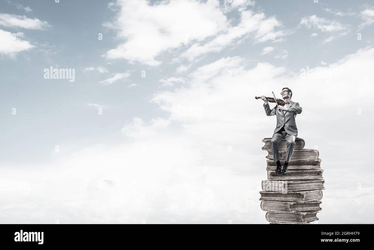 Handsome Violinist In Blue Day Sky On Pile Of Books Play His Melody Stock Photo Alamy