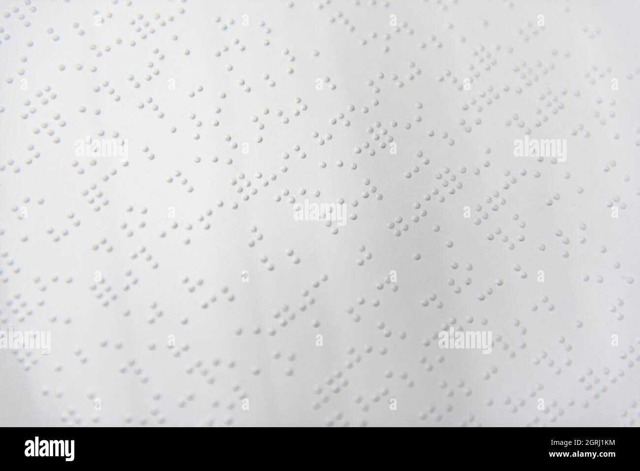 A fragment of text in Louis Braille printed on a standard sheet of paper using special printing equipment. Stock Photo