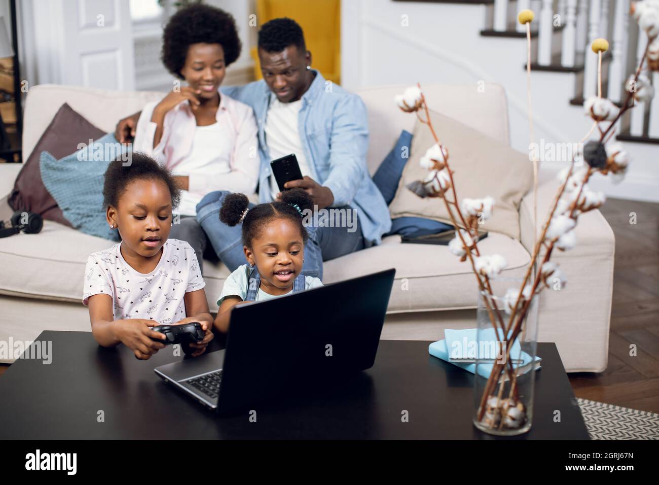 Cute african american sisters using laptop and joysticks for playing ...