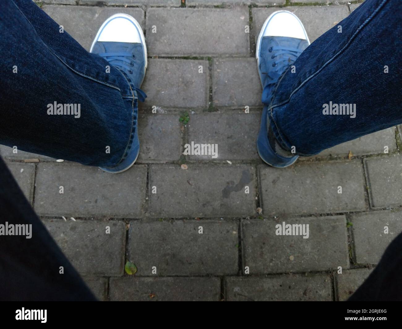 Low Section Of Man Wearing Shoes While Standing On Pavement Stock Photo