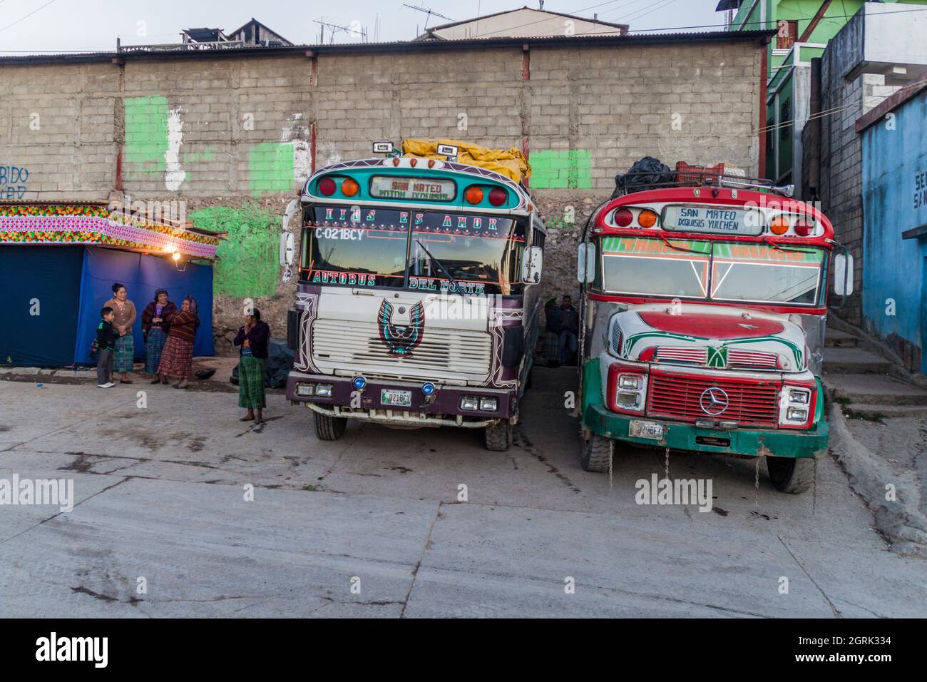 SAN MATEO IXTATAN, GUATEMALA, MARCH 19, 2016: Colourful chicken buses, former US school buses, wait in San Mateo Ixtatan village. Stock Photo