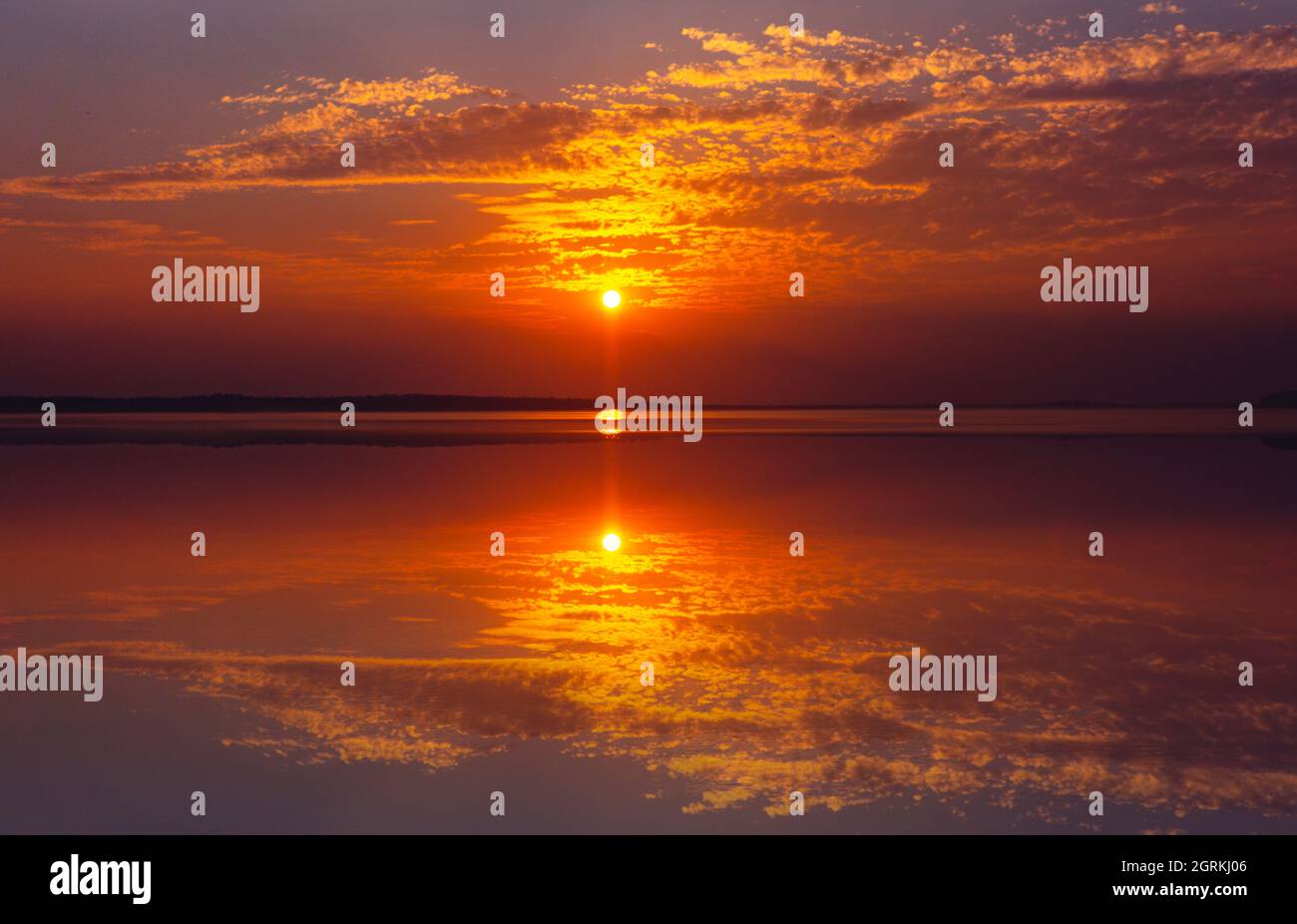Orange And Gold Sky At Sunset Reflecting In Perfect Lake Stock Photo