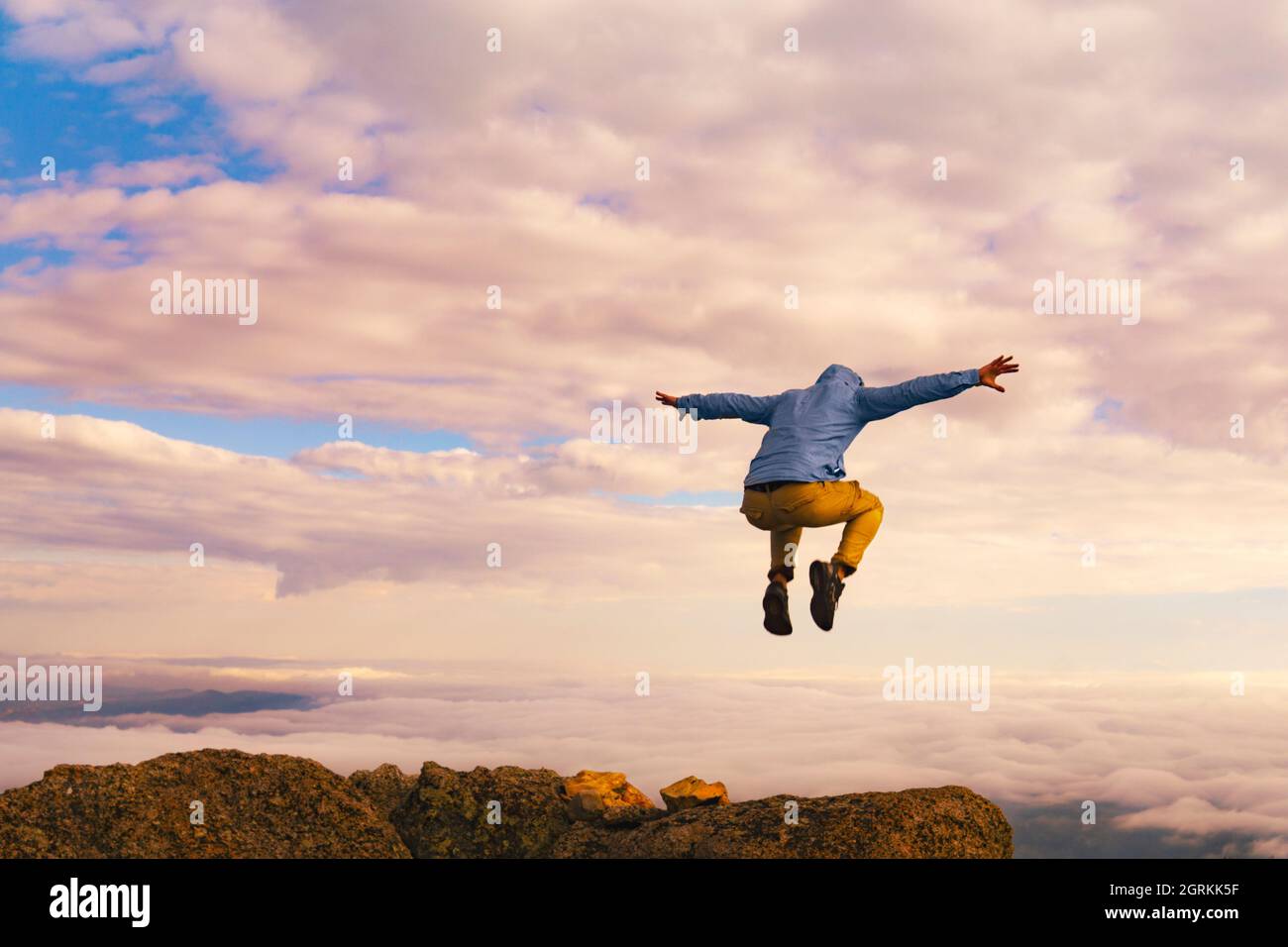 Man Jumping On Mountain Summit Peak Top Successful Winning Concept Above Clouds Stock Photo