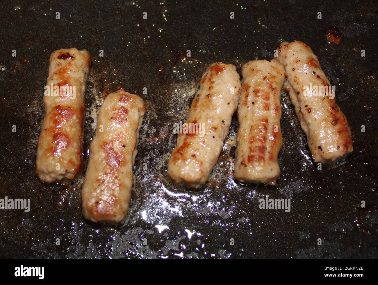 Five sausage links cooking on a griddle. Stock Photo