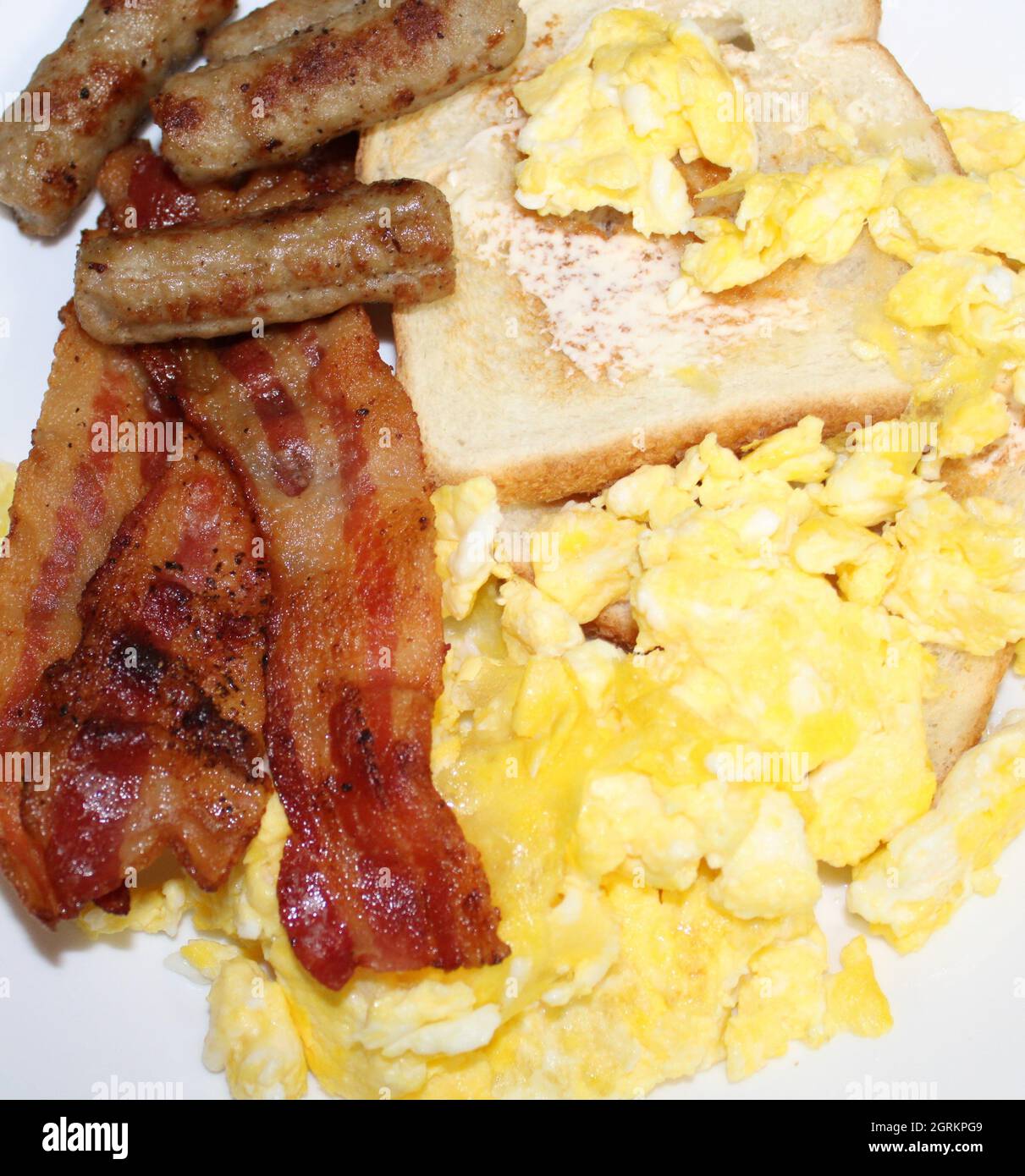 Delicious breakfast consisting of bacon, sausage, eggs and toast. Stock Photo