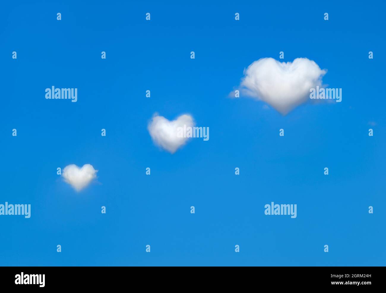 White, fluffy heart shaped clouds in bright blue sky. Concept of love ...