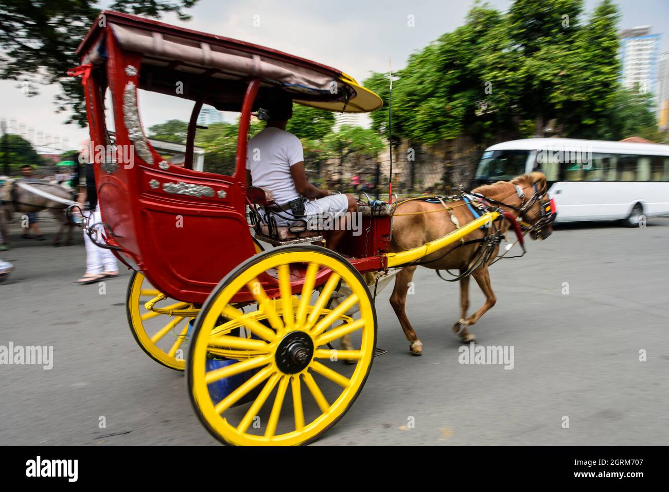 A passing two-wheeled horse-drawn carriage (kalesa) in Manila, Philippines. Stock Photo