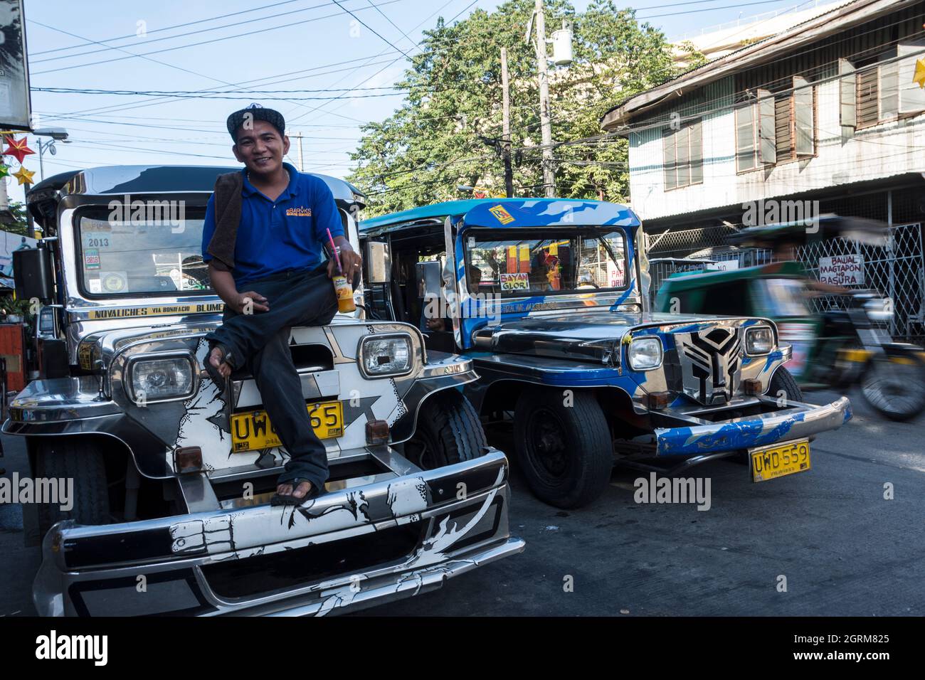 Busdriver taking a break sits on the hood of his jeepney. Manila, Philippines. Stock Photo