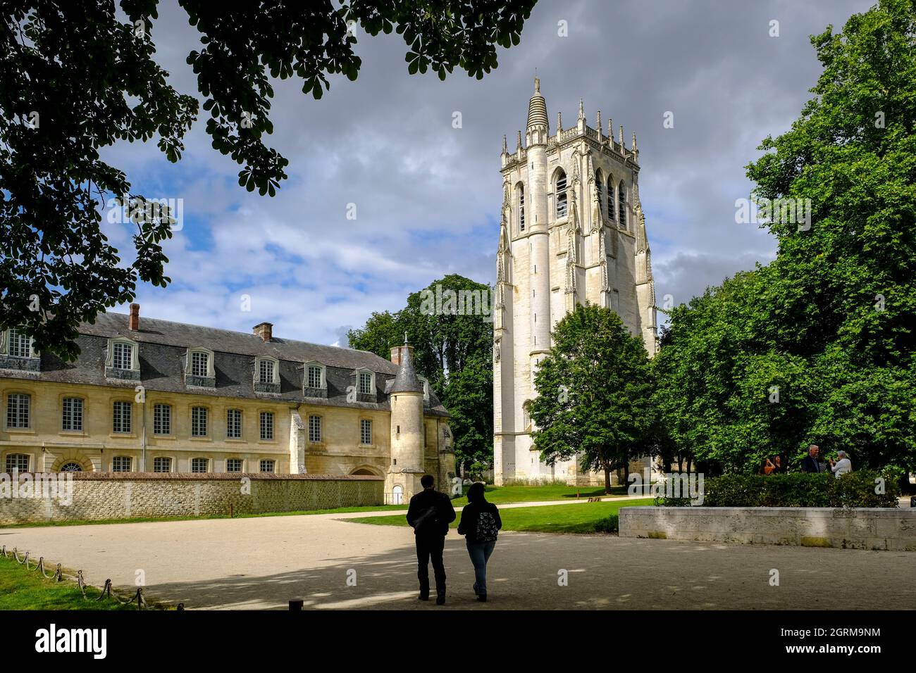 Frankreich, Le Bec-Hellouin, 28.08.2021: Zwei Besucher auf dem Gelaende der Abtei Le Bec mit dem Turm Saint-Nicolas im normannischen Dorf Le Bec-Hello Stock Photo