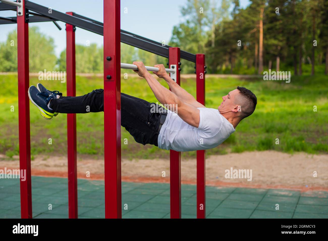 Caucasian man doing a back plank on the uneven bars. Workout on sports ground Stock - Alamy