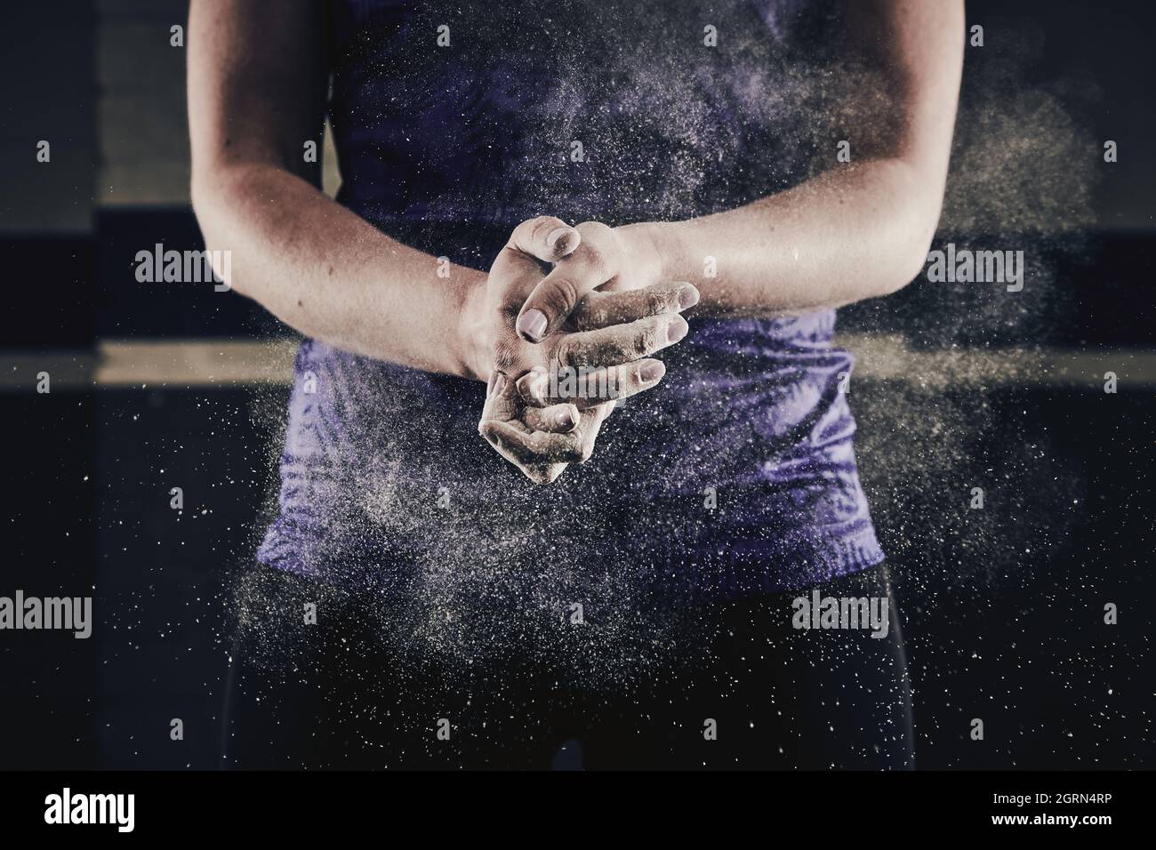 Female athlete clapping hands with chalk dust for weight lifting Stock Photo