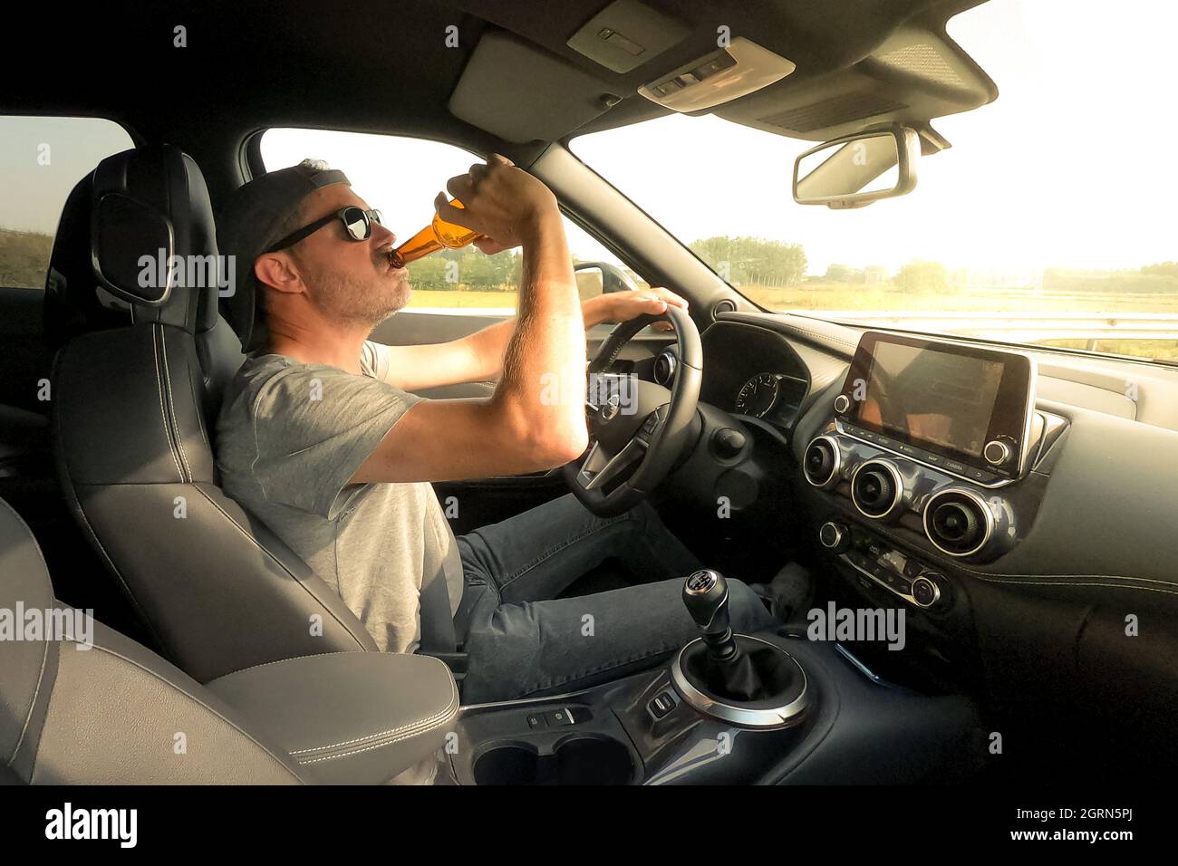 Man drive a car and drink a beer. Driver young male drinking alcoholic