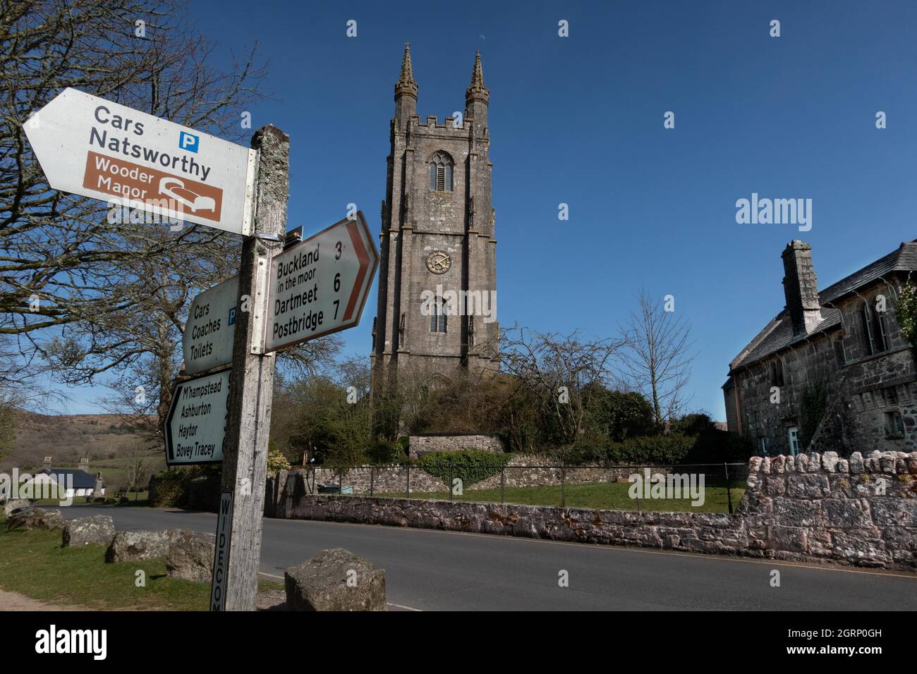 St Pancras Church and signpost on the village green at Widecombe in the Moor on Dartmoor Devon England Stock Photo