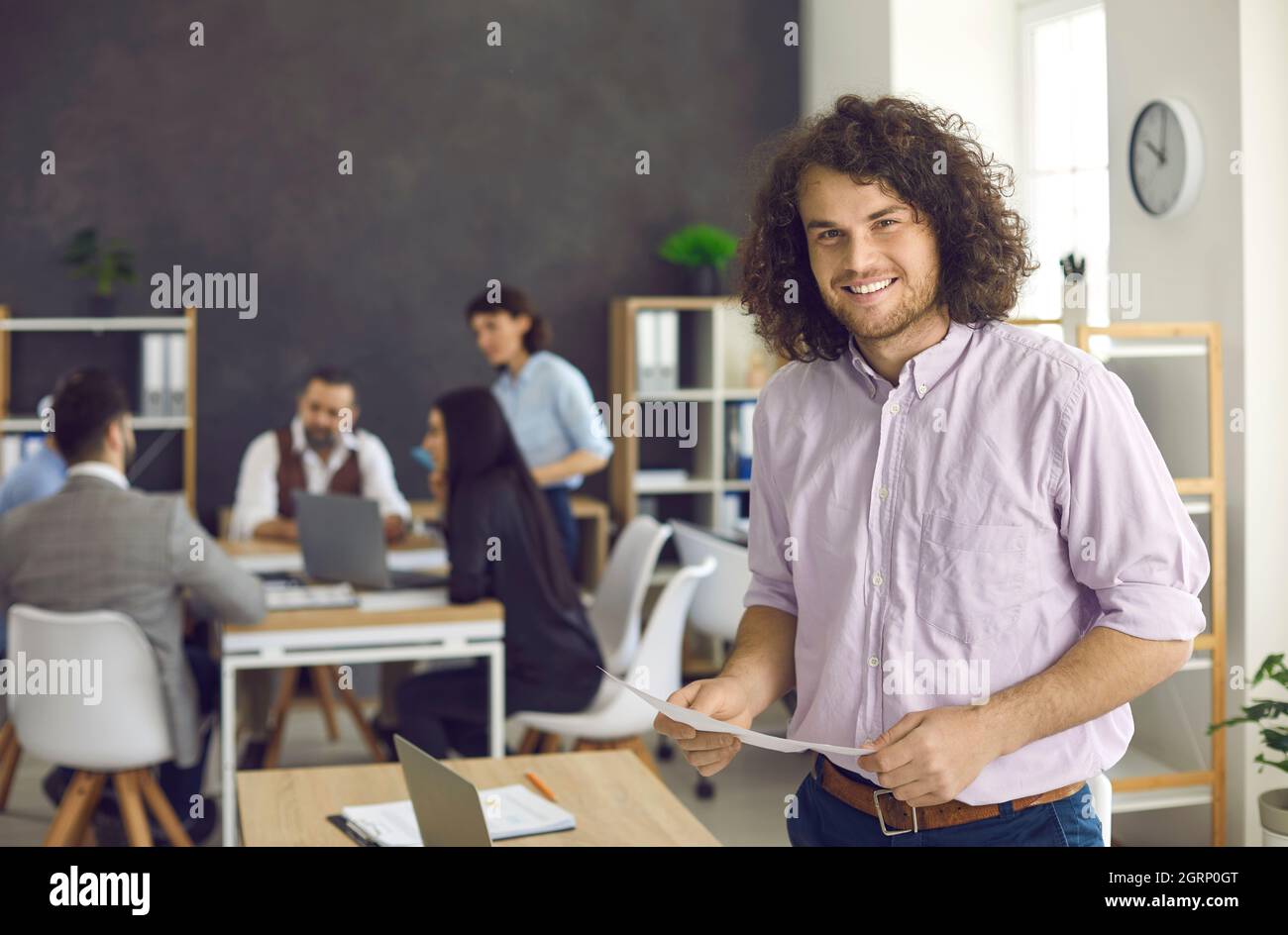 Portrait of a happy smiling young businessman standing in a modern ...