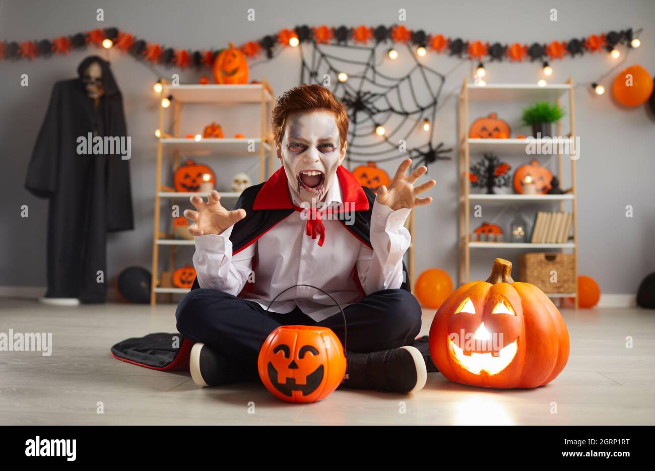 Terrifying child in traditional Halloween vampire costume who screams and scares looking at camera. Stock Photo