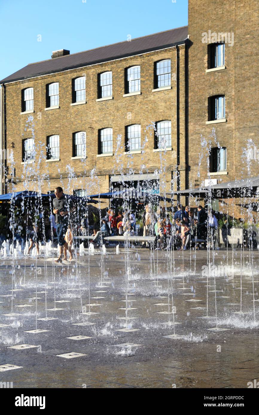 Autumn sunshine on the fountains in Granary Square, with St Martins Central School of Art behind, at Kings Cross, in London, UK Stock Photo