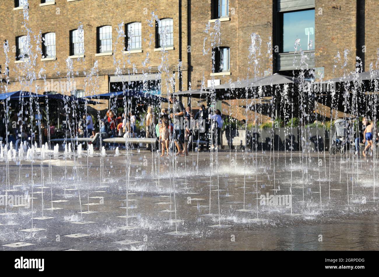 Autumn sunshine on the fountains in Granary Square, with St Martins Central School of Art behind, at Kings Cross, in London, UK Stock Photo