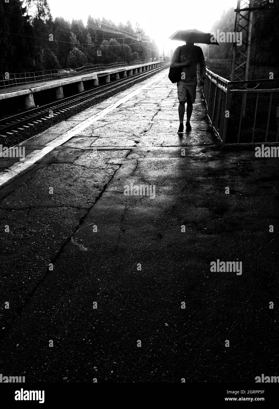 Man With Umbrella Walking On Railroad Station Platform Stock Photo