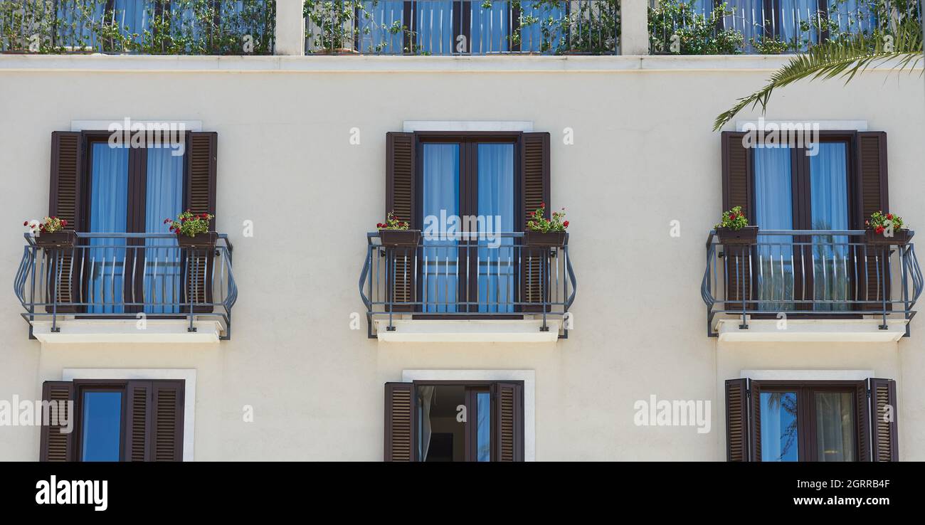 Modern windows in an apartment with wrought iron railings and flowers Stock Photo