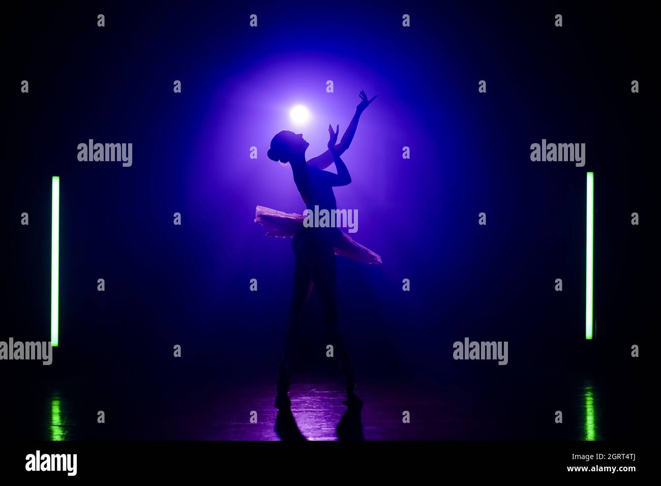 Silhouette of theater dancer in tutu on violet spotlight background. Woman ballerina dancing classical dance elements. Lightness, femininity and Stock Photo