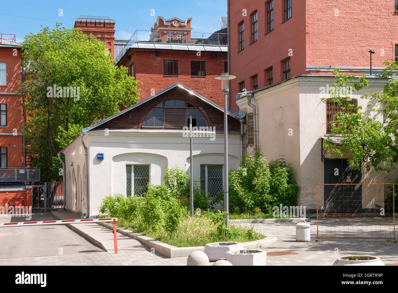 Small one-story house between large industrial buildings Stock Photo