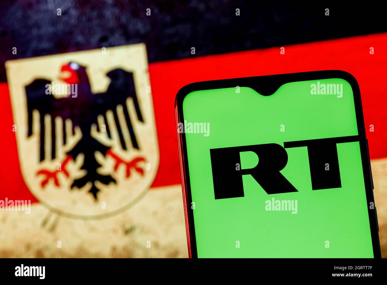 Smartphone with RT (Russia Today) logo on the background of the flag of Germany. Blocking RT DE YouTube channels in Germany. Stock Photo