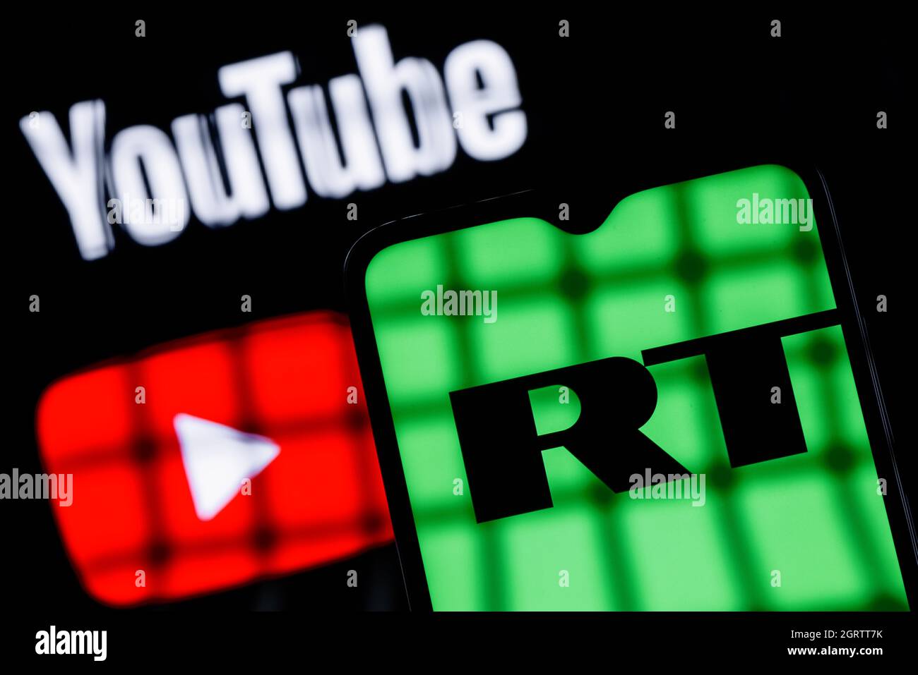 Behind bars is a smartphone with the RT (Russia Today) logo on the background of the Youtube logo. Blocking RT (Russia Today) YouTube channels. Stock Photo