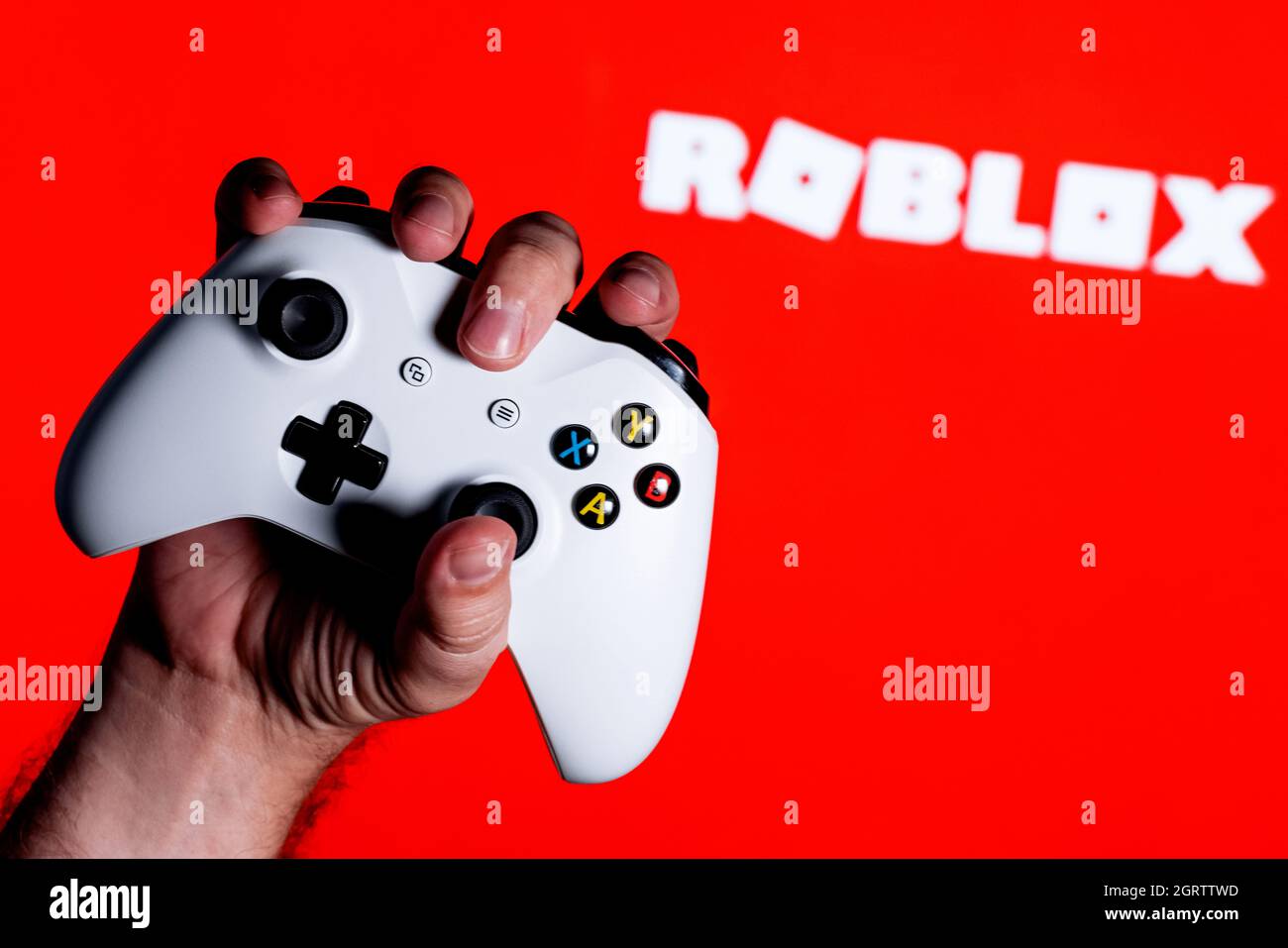 Roblox is an online game platform and game creation system. A white gamepad  clutched in the hand on the red background with the logo of Roblox Stock  Photo - Alamy