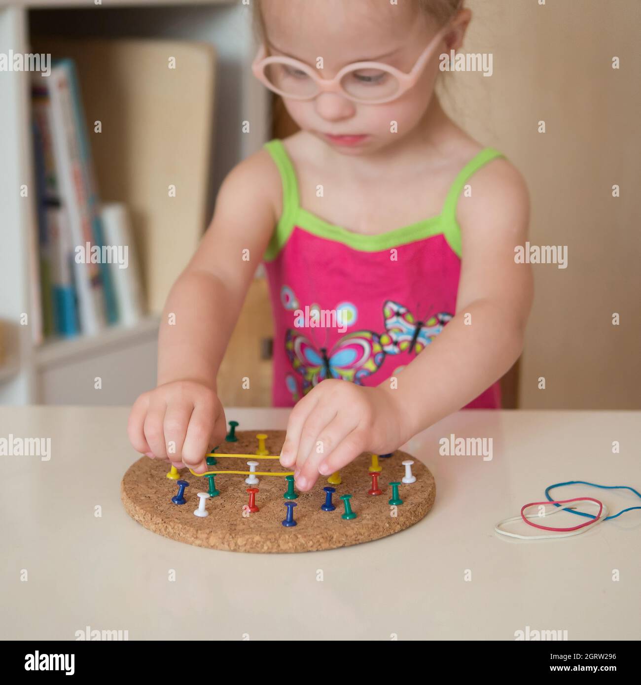 Girl with Down syndrome develops fine motor skills of hands Stock Photo