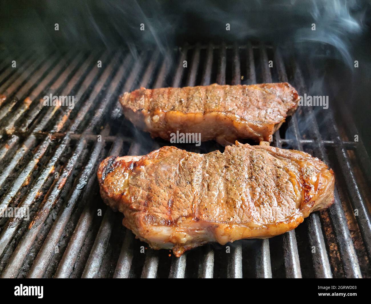 Beef sirloin steaks cooking on a barbeque grill Stock Photo