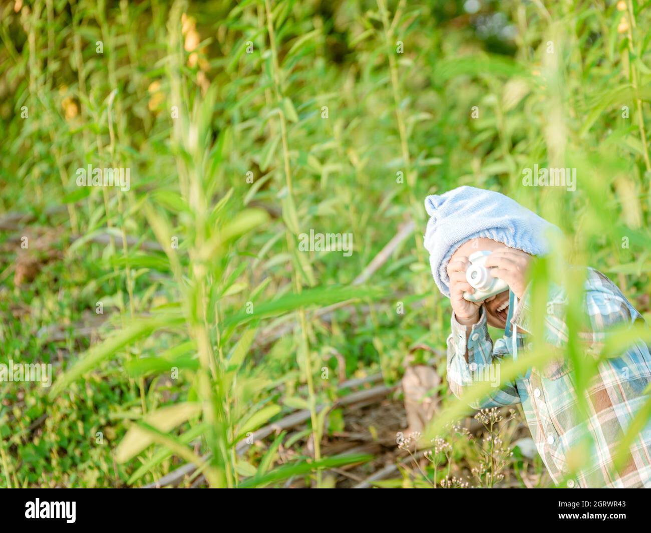 Girl Holding Toy Camera Amidst Plants Stock Photo