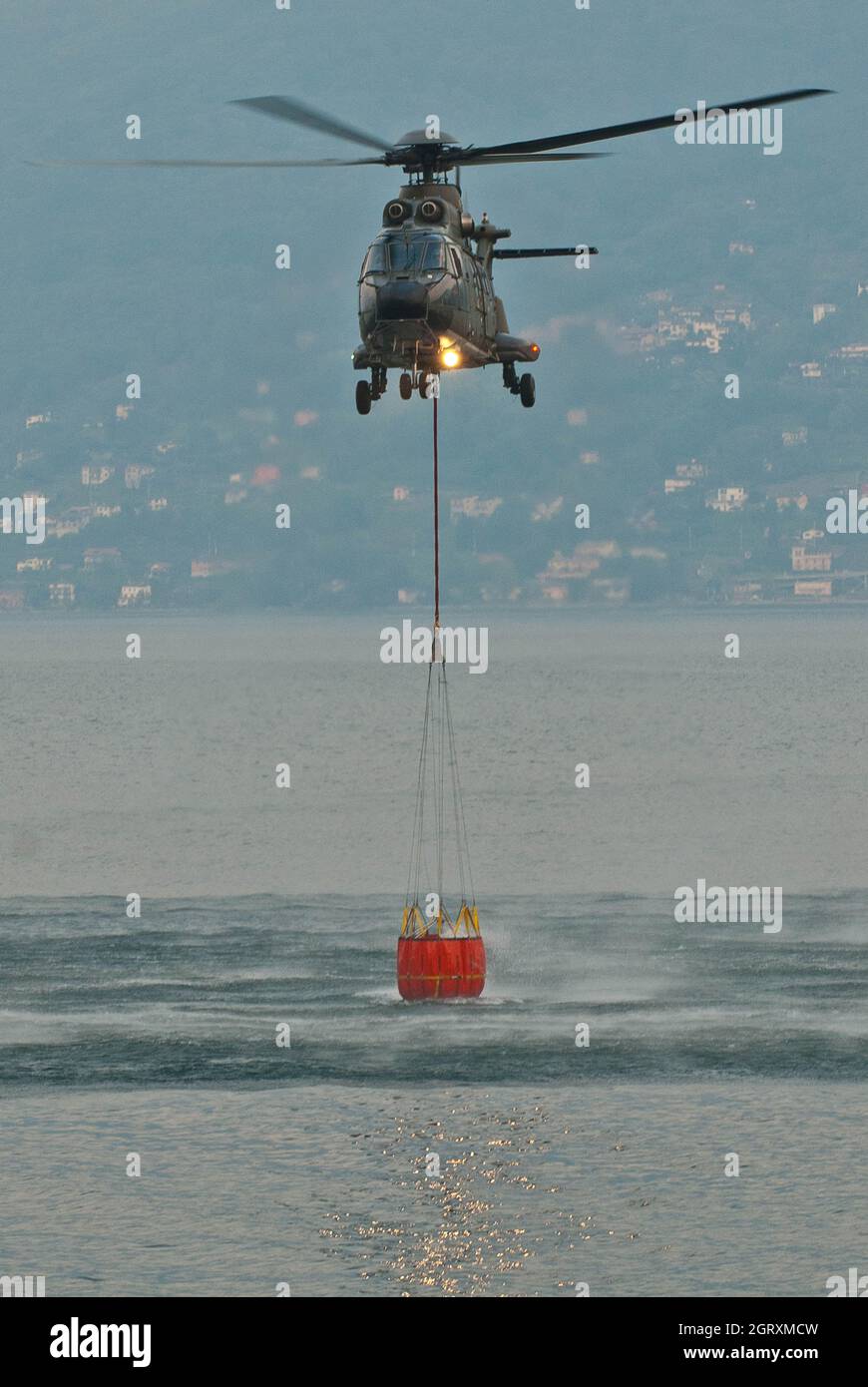 Helicopter Carrying Water In Container Over Sea Stock Photo Alamy
