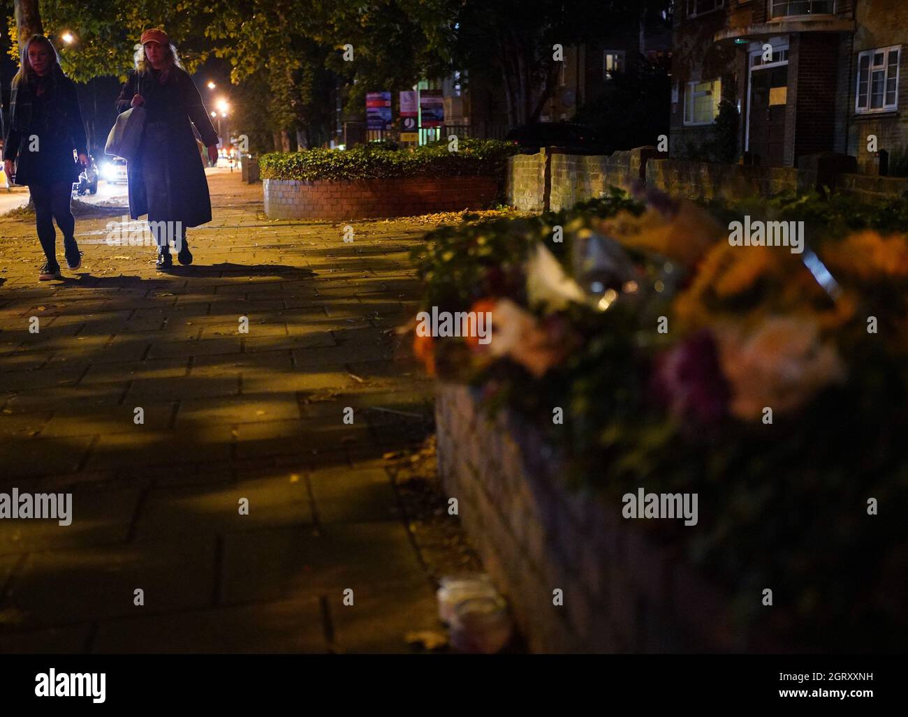 Two woman walking after dark past floral tributes to Sarah Everard on Poynders Road in Clapham, south London, close to where Sarah Everard was abducted from the street by being falsely arrested by police officer Wayne Couzens in March. Picture date: Friday October 1, 2021. Stock Photo