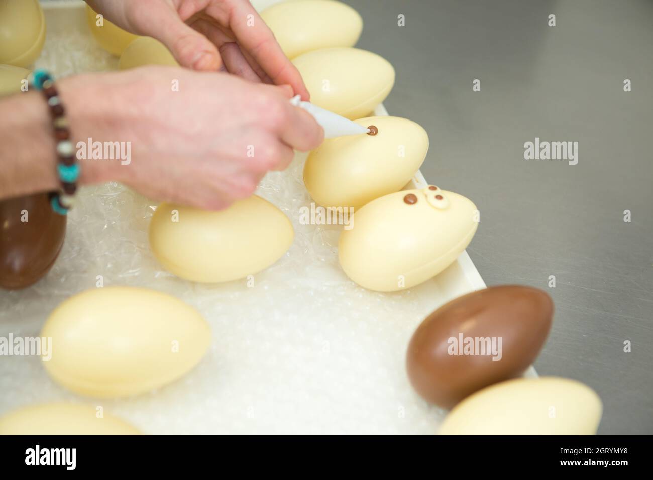 hand decorating a white chocolate egg Stock Photo