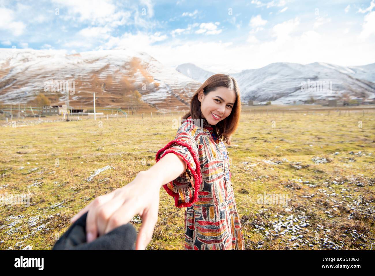 Side View Portrait Of Woman Standing On Field Against Snowcapped Mountains Stock Photo