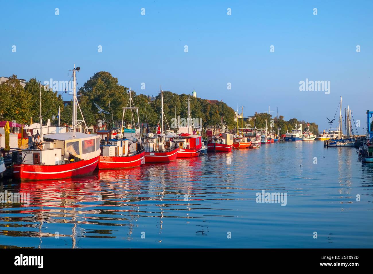 A line of red tourist and fishing boats line the Alter Strom Canal in the coastal resort of Warnemunde on the Baltic Sea. Stock Photo