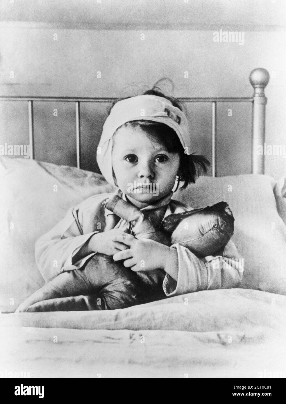 Eileen Dunne, aged three, sits in bed with her doll at Great Ormond Street Hospital for Sick Children, after being injured during an air raid on London in September 1940. Photo by Cecil Beaton Stock Photo