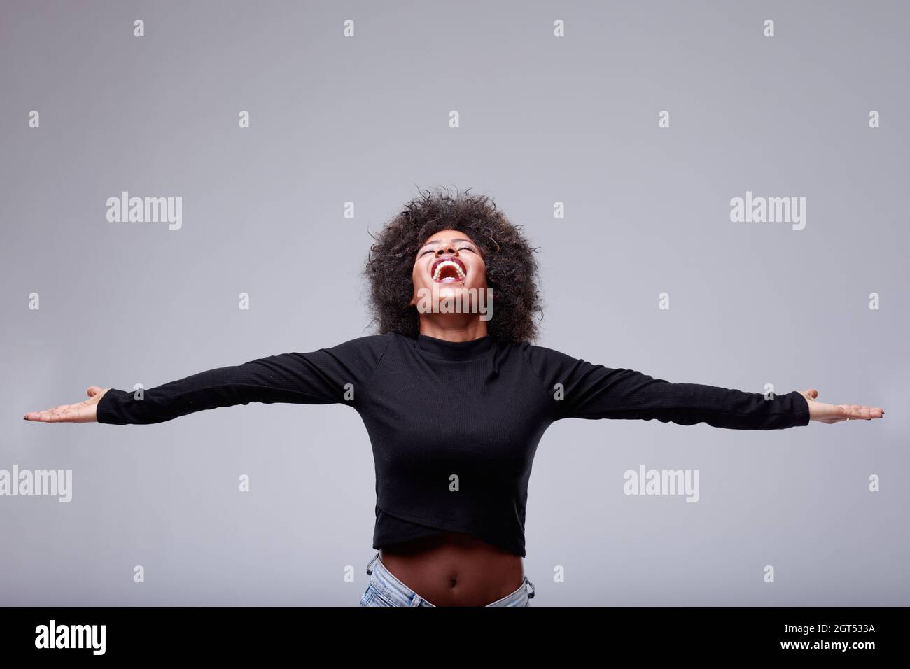 Joyful exuberant young Black woman celebrating with open arms and her