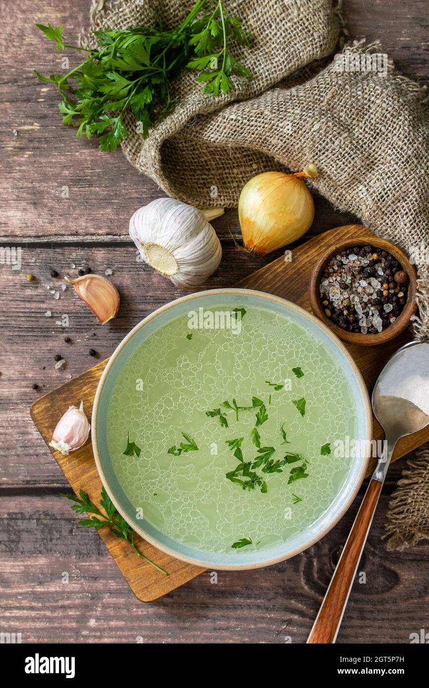 Hot Rich Meat Broth, Bouillon With Herbs On A Rustic Table. Top View