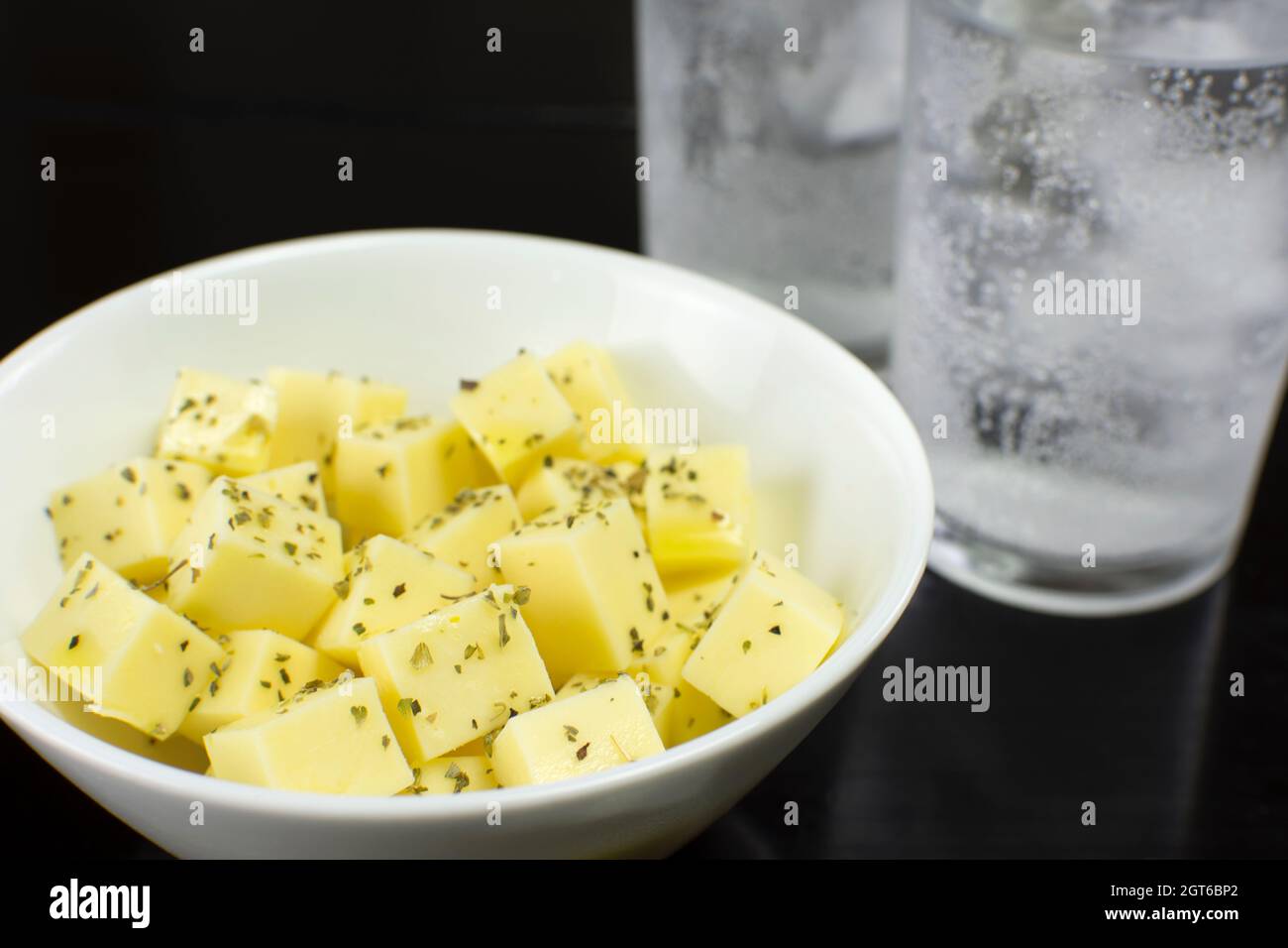 Mozzarella Cheese Cubes In A White Bowl In A Black Table With Two Cups