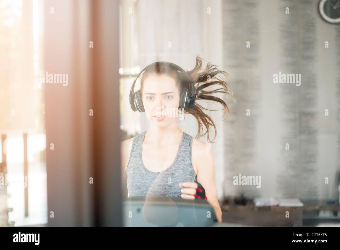 Portrait Of Young Woman In Gym Seen Through Window Glass Stock Photo