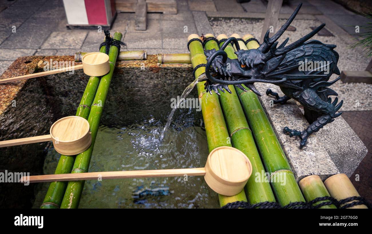 Purification by washing hand at the fountain of sanctuary in Kyoto. Water running from mouth of a dragon at Japan. Entrance of a Japanese shinto templ Stock Photo