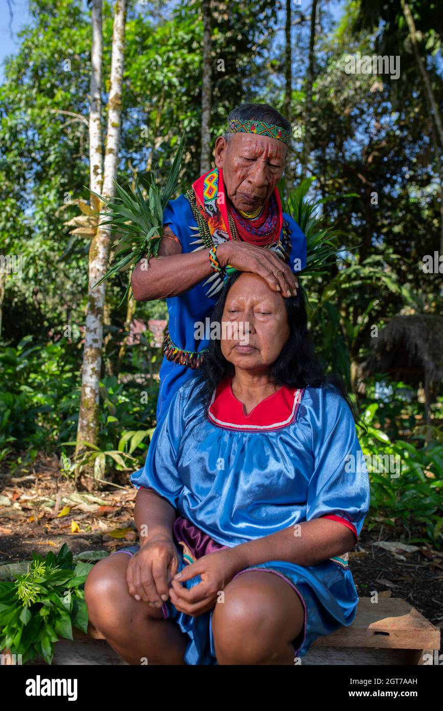 Nueva Loja, Sucumbios / Ecuador - September 2 2020: Elderly indigenous shaman of Cofan nationality performing healing ritual to a Cofan woman in the A Stock Photo