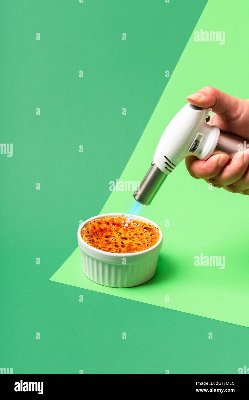 Making Creme Brulee In A Ramekin, On A Green Background. Woman Burning