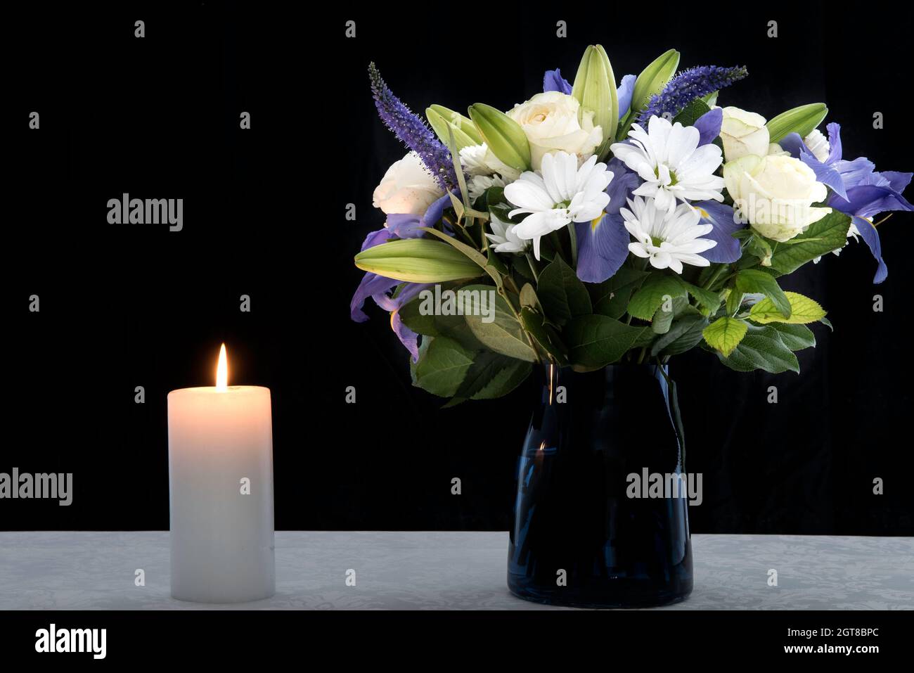 Funeral Bouquet purple White flowers and burning white candle