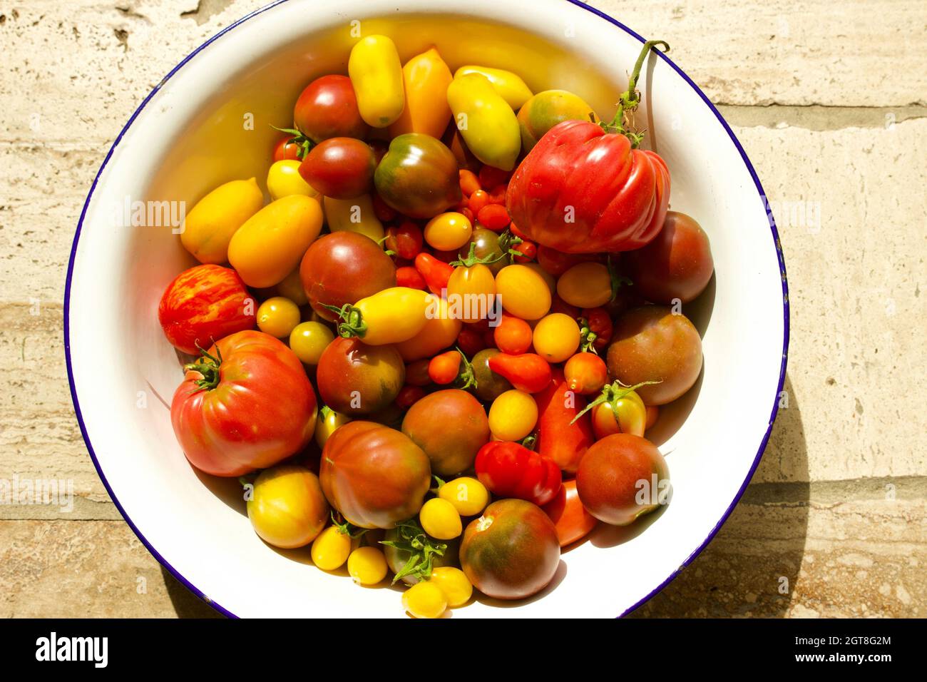 High Angle View Of Mixet Tomatos In Bowl On Sotne Stock Photo