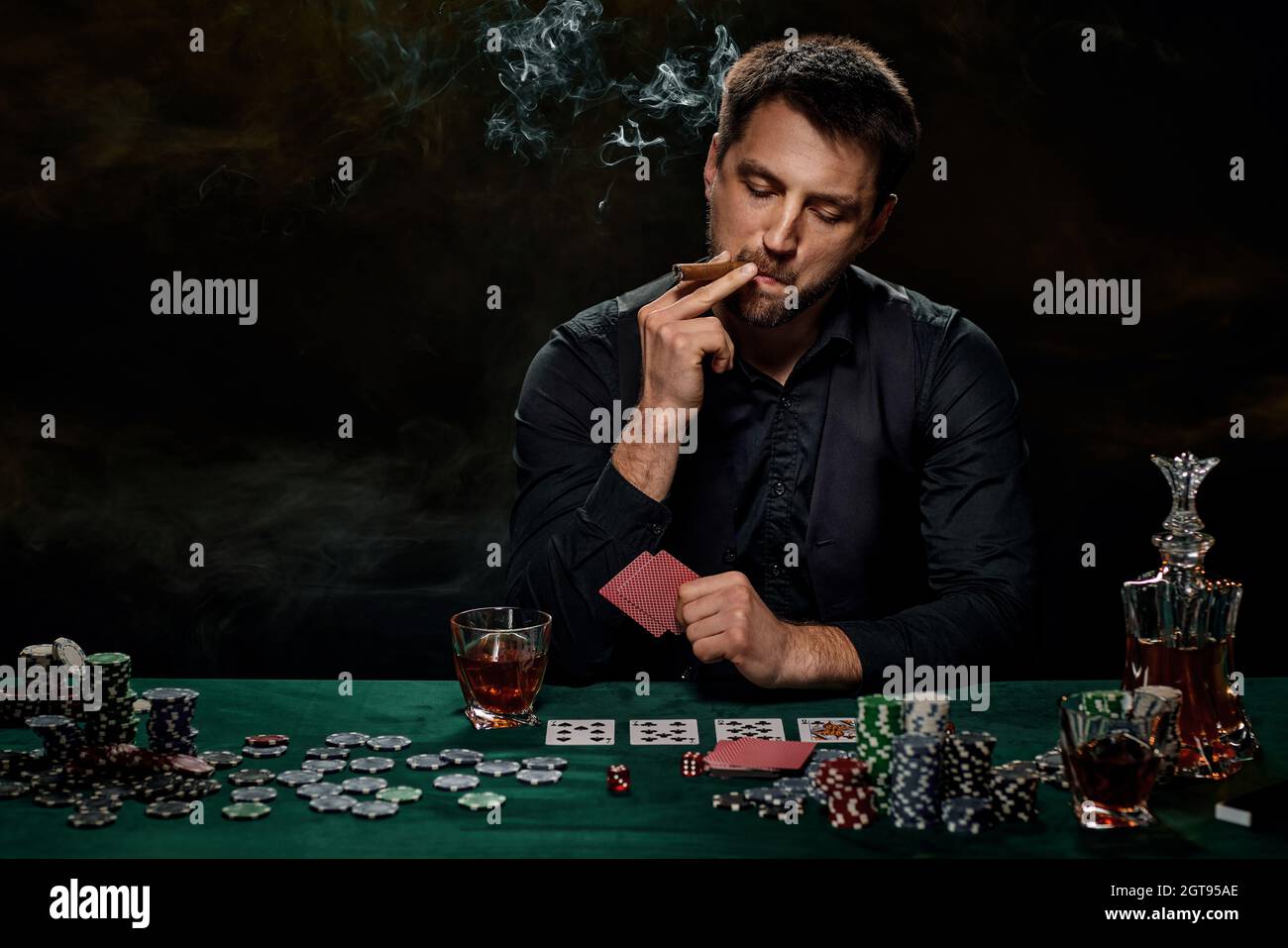 Bearded casino player man playing poker on green table Stock Photo