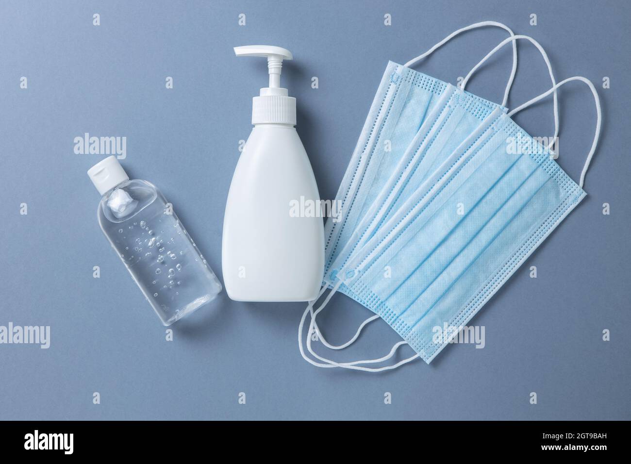 Medical Protective Blue Face Masks, Sanitizer Gel, Hand Soap On Gray Background, Flatly, Minimal Stock Photo