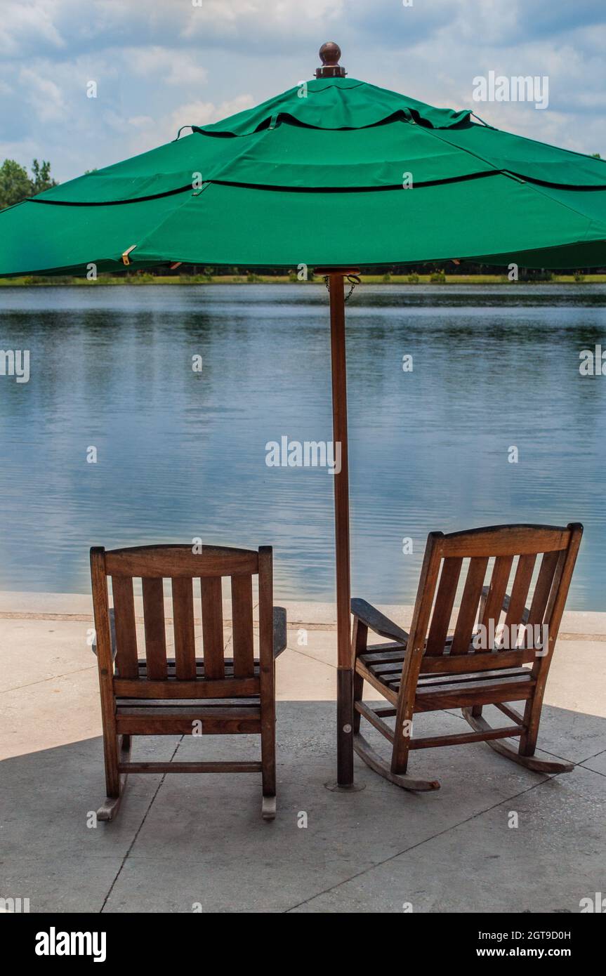 Two Wood Rocking Chairs Under Green Umbrella On Cement Deck Near Lake Stock  Photo - Alamy